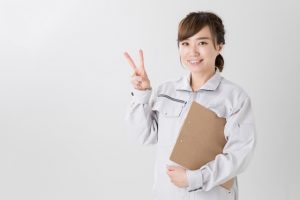 ピースサインの作業着の女性の写真画像